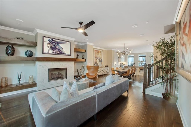 living room with ceiling fan with notable chandelier, dark wood-type flooring, and ornamental molding