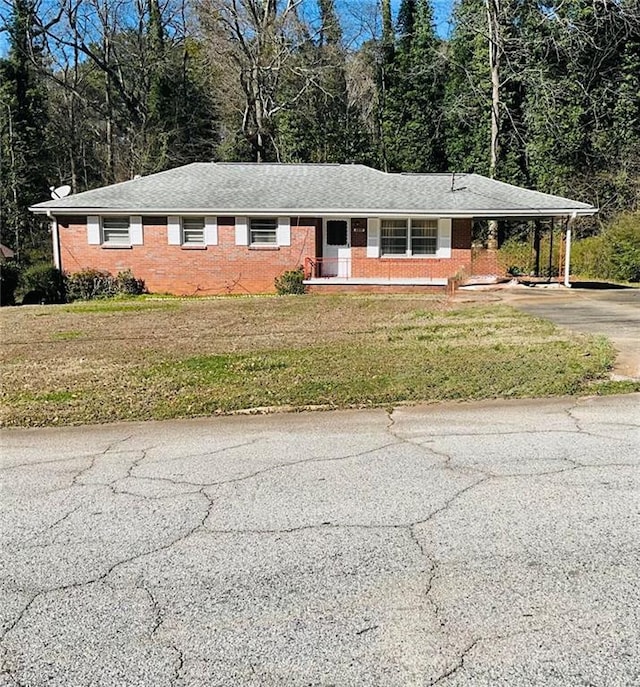 ranch-style house with an attached carport, a front yard, brick siding, and concrete driveway