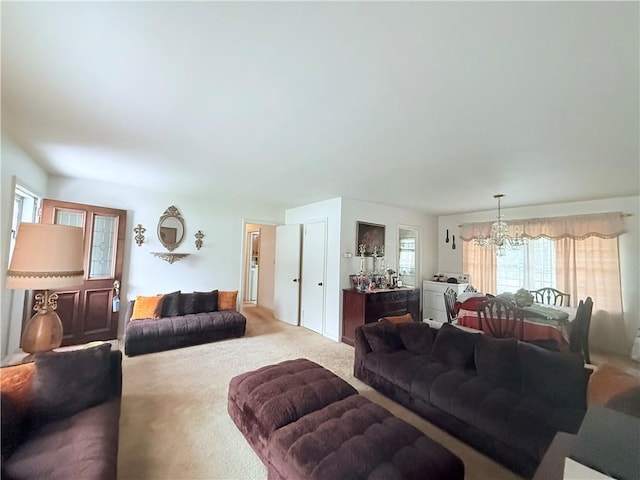 carpeted living room featuring washer and clothes dryer and a chandelier