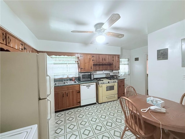kitchen with white appliances, a ceiling fan, light floors, a sink, and brown cabinetry