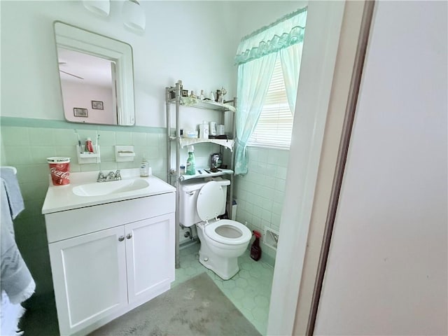 bathroom featuring toilet, vanity, tile walls, and wainscoting