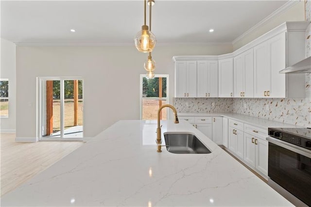 kitchen featuring sink, white cabinets, stainless steel oven, light stone counters, and pendant lighting