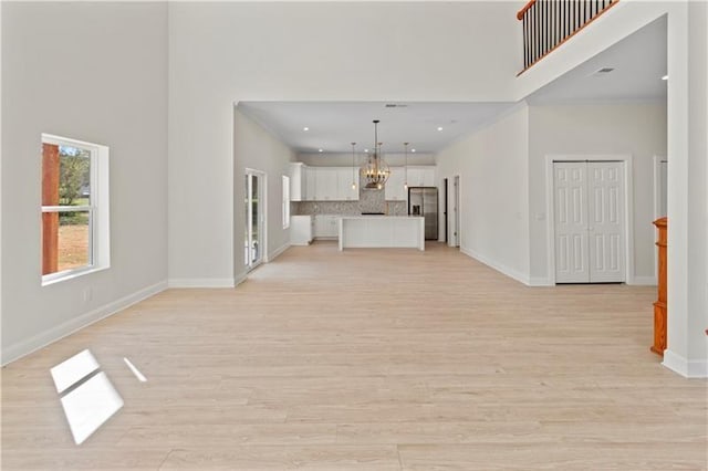 unfurnished living room with a towering ceiling and light hardwood / wood-style floors