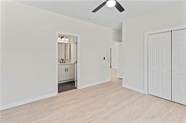 unfurnished bedroom with light wood-type flooring, ceiling fan, a closet, and connected bathroom