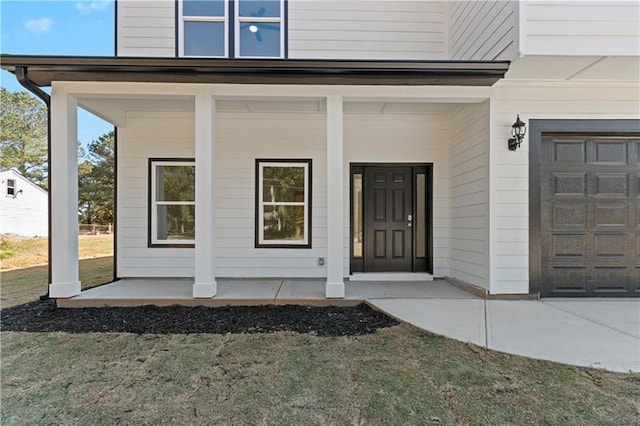 view of exterior entry featuring covered porch and a lawn