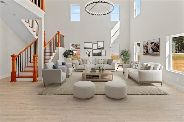 living room featuring a towering ceiling, light hardwood / wood-style flooring, and plenty of natural light