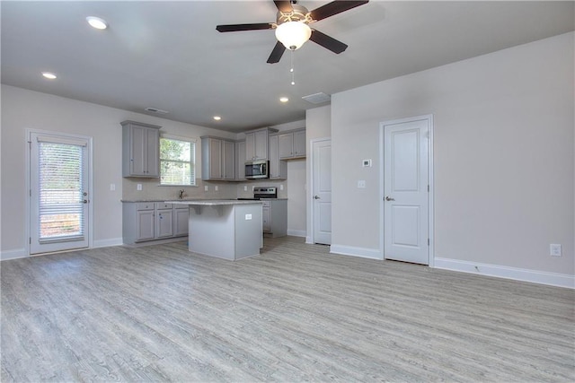 kitchen featuring gray cabinets, decorative backsplash, a center island, ceiling fan, and light hardwood / wood-style floors