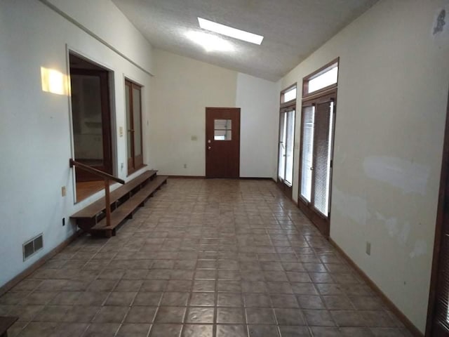 interior space with dark tile flooring and lofted ceiling with skylight