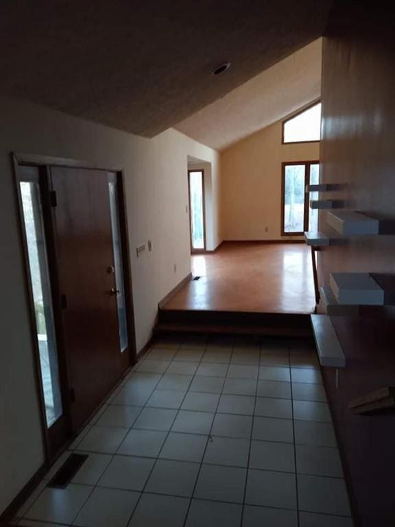 interior space with light tile floors and vaulted ceiling