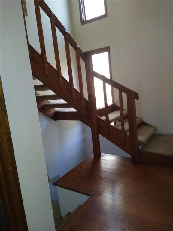 stairway with dark wood-type flooring and a high ceiling