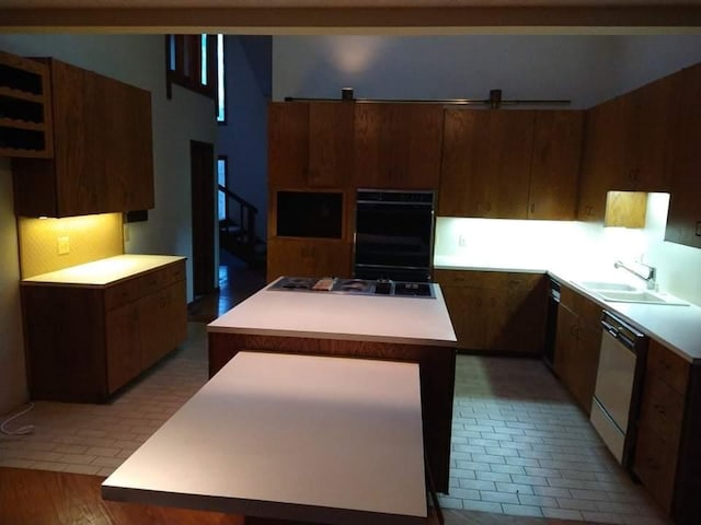 kitchen with dark wood-type flooring, black appliances, sink, a center island, and tasteful backsplash