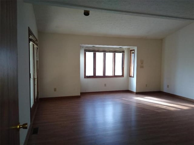 unfurnished room featuring dark hardwood / wood-style flooring and a textured ceiling