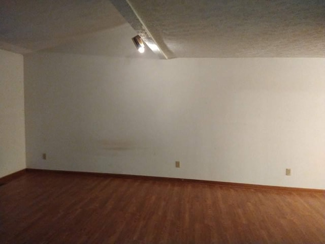 spare room with a textured ceiling and dark hardwood / wood-style flooring