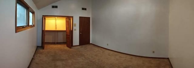 unfurnished bedroom with a closet, high vaulted ceiling, a spacious closet, and light colored carpet