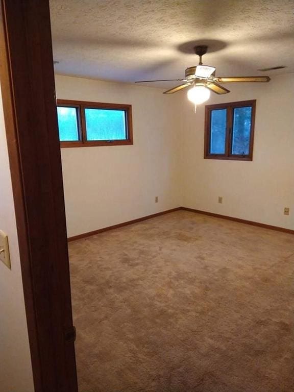 carpeted empty room featuring a textured ceiling and ceiling fan