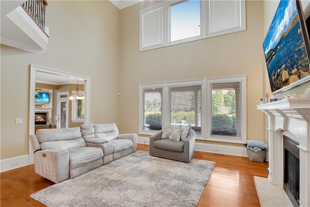 living area featuring light wood-style flooring, a fireplace, a high ceiling, and crown molding