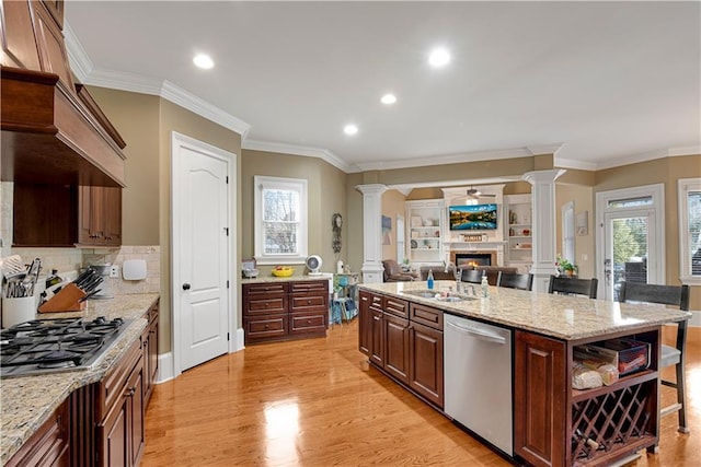 kitchen featuring ornate columns, a lit fireplace, stainless steel appliances, and a wealth of natural light