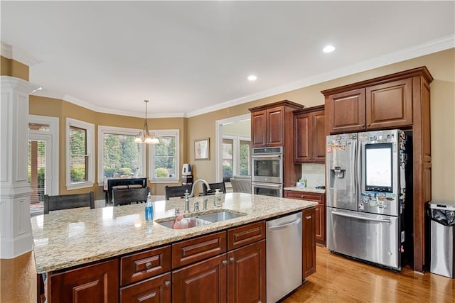 kitchen featuring ornate columns, a kitchen island with sink, stainless steel appliances, and a sink