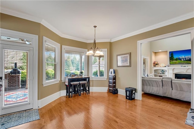 dining room featuring ornamental molding, light wood finished floors, baseboards, and a notable chandelier