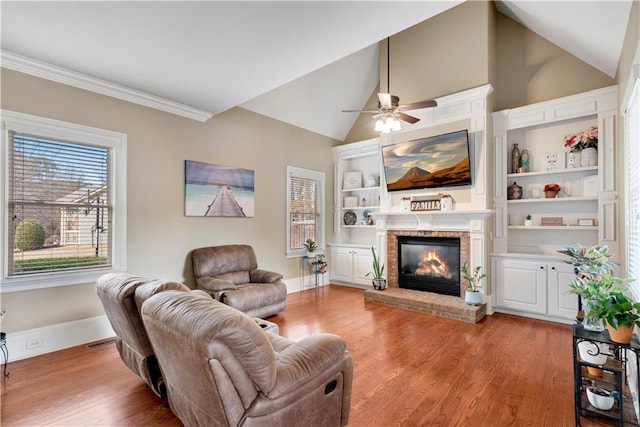 living room featuring a brick fireplace, baseboards, vaulted ceiling, and wood finished floors