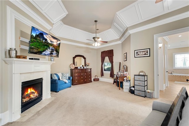 sitting room featuring carpet, ornamental molding, ceiling fan, and a fireplace with flush hearth