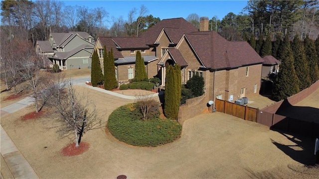 view of front facade featuring driveway, a residential view, and fence