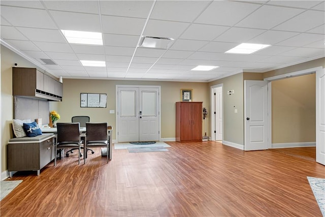 office space with a drop ceiling, visible vents, baseboards, light wood-style floors, and ornamental molding