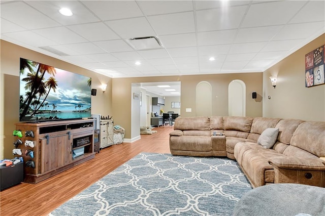 living room featuring arched walkways, crown molding, recessed lighting, light wood-style floors, and baseboards