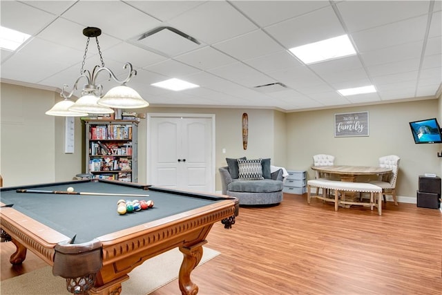 rec room with a drop ceiling, light wood-type flooring, and crown molding