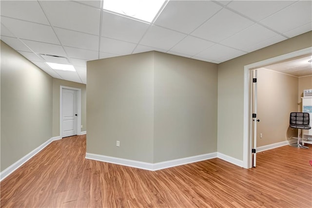 interior space featuring a paneled ceiling, light wood-style floors, and baseboards