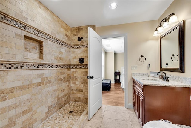 full bath featuring tile patterned flooring, connected bathroom, vanity, baseboards, and walk in shower