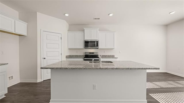 kitchen with white cabinets, a sink, stainless steel appliances, and light stone counters