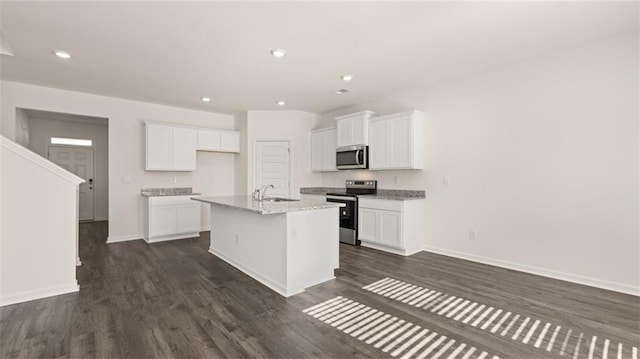 kitchen with a sink, white cabinetry, appliances with stainless steel finishes, dark wood finished floors, and a center island with sink