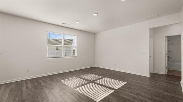 unfurnished room featuring visible vents, baseboards, and dark wood finished floors