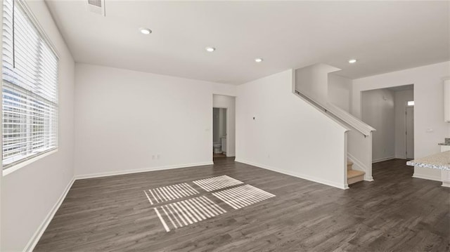 unfurnished room featuring dark wood finished floors, stairs, baseboards, and recessed lighting