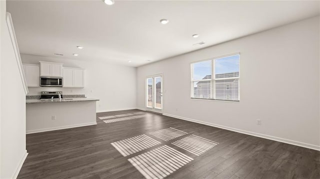 unfurnished living room with dark wood-style flooring, visible vents, baseboards, and recessed lighting