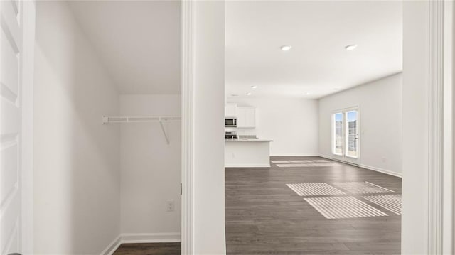 walk in closet with dark wood finished floors