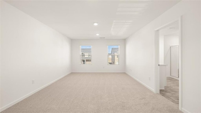 spare room featuring baseboards and light colored carpet