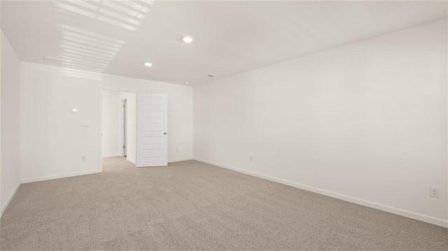 empty room with light carpet, baseboards, and recessed lighting