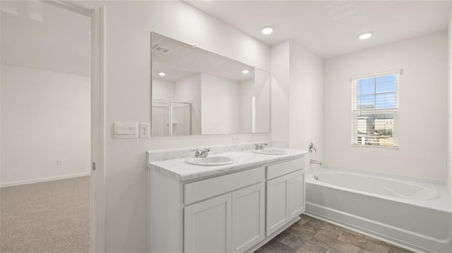 bathroom featuring double vanity, a sink, baseboards, and a garden tub