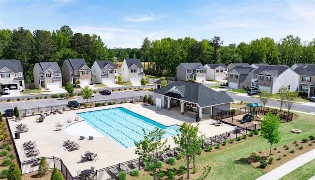 community pool featuring fence, a patio area, and a residential view