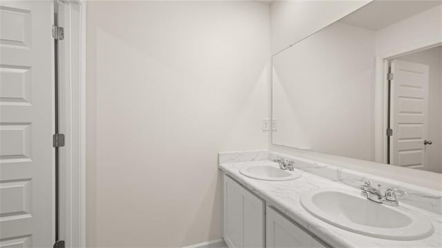 bathroom with double vanity, a sink, and baseboards