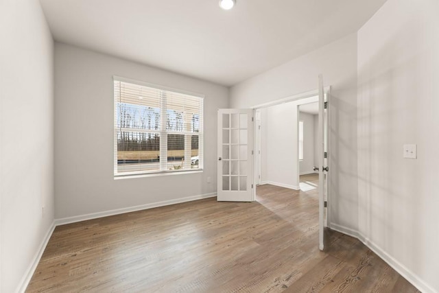 empty room with baseboards, wood finished floors, and french doors