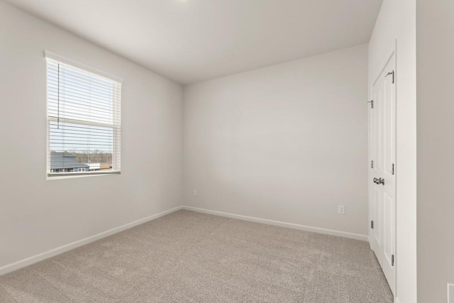 unfurnished room featuring light carpet and baseboards