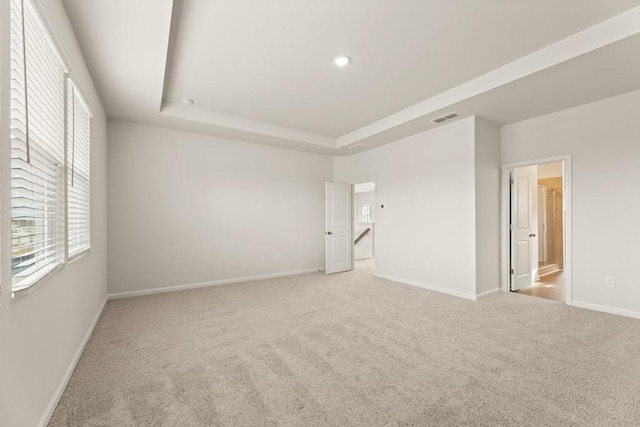 carpeted empty room with recessed lighting, a raised ceiling, visible vents, and baseboards