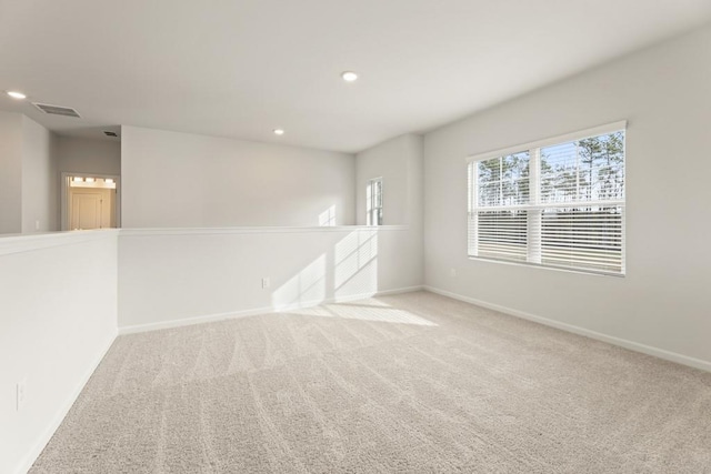 carpeted spare room featuring baseboards, visible vents, and recessed lighting