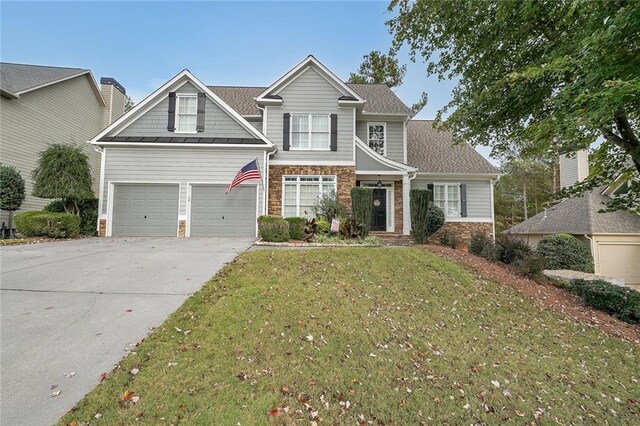 craftsman inspired home featuring a garage and a front lawn