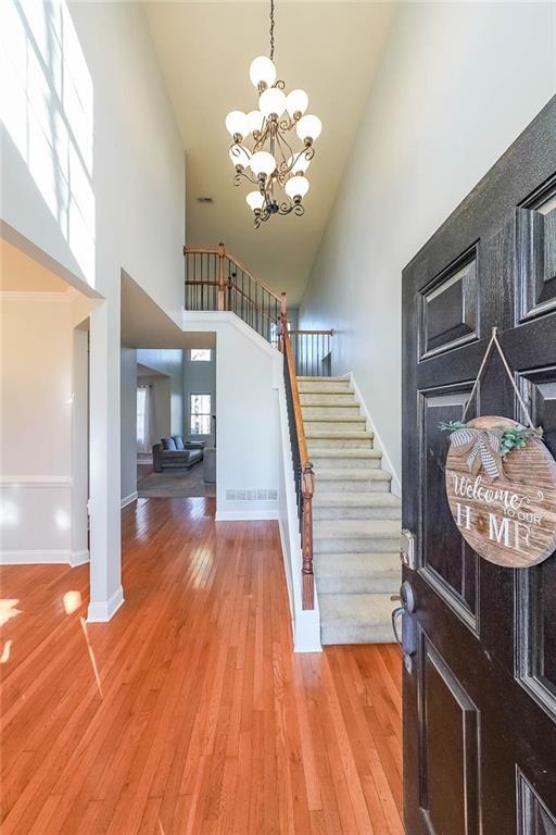 foyer entrance featuring hardwood / wood-style floors, a towering ceiling, and a notable chandelier