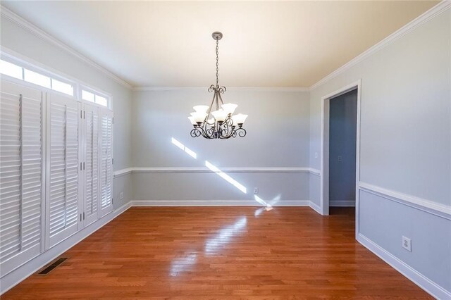 unfurnished dining area with hardwood / wood-style floors, an inviting chandelier, and ornamental molding