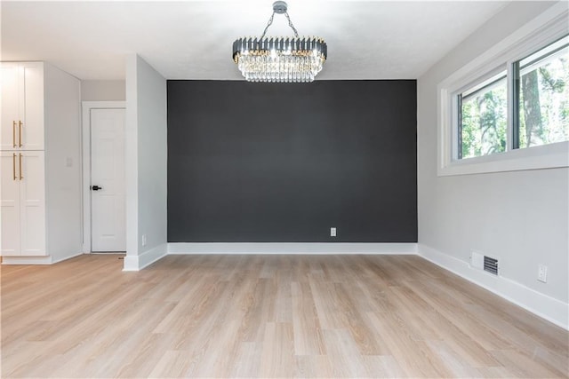 spare room with light hardwood / wood-style flooring and a notable chandelier